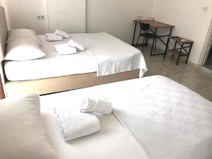 two beds in a room with white sheets and towels at Ayvaz Otel in Torbalı