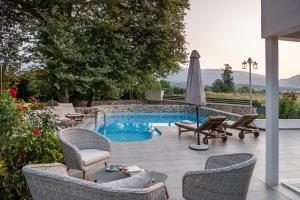 a patio with a pool and chairs and an umbrella at Villa Nature, Heated Pool in Kalyves