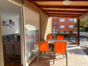 un patio con sillas naranjas y una mesa en un patio en Apartman MERI, en Strmec Samoborski