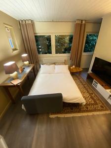 a bedroom with a bed and a desk and two windows at Studio & Appartement au Lac in Sart-lez-Spa