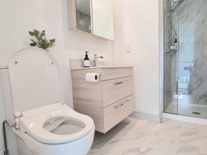 a white bathroom with a toilet and a shower at Elegant CBD Apartment in Christchurch