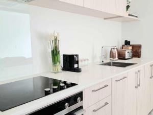 a kitchen with white cabinets and a black appliance at Elegant CBD Apartment in Christchurch