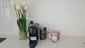a counter with a hair dryer and a blender and flowers at Elegant CBD Apartment in Christchurch