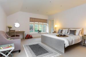 una grande camera da letto con un grande letto e una sedia di Windrush a Colesbourne
