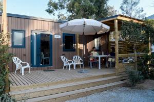 una terraza de madera con mesa y sombrilla en Camping Bella Vista en Calvi