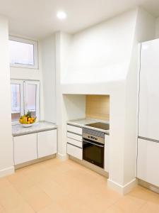 a kitchen with white cabinets and a bowl of fruit on the counter at Room in the Heart of Historic Lisbon on Rua Augusta in Lisbon