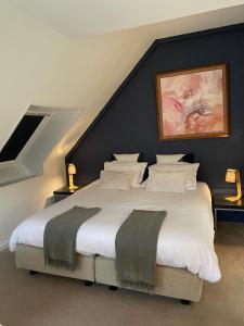1 dormitorio con 1 cama grande con sábanas y almohadas blancas en Studio & Appartement au Lac, en Sart-lez-Spa