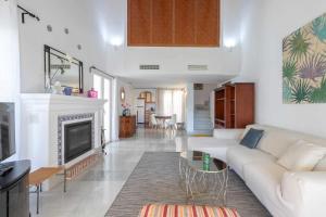 een woonkamer met een witte bank en een open haard bij Golf Duplex con piscina en La Quinta Golf Marbella in Málaga