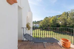 een balkon met een bank en uitzicht op een tuin bij Golf Duplex con piscina en La Quinta Golf Marbella in Málaga