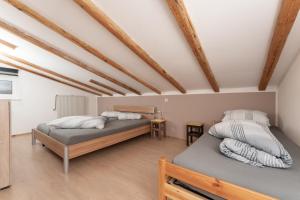 two beds in a room with wooden beams at Haus Attos in Umhausen
