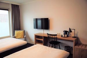 a hotel room with a desk and a tv on the wall at Golden Tulip Keyser Breda Centre in Breda