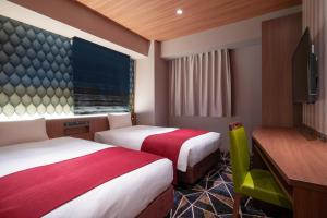 una camera d'albergo con due letti e una televisione di the b sapporo a Sapporo