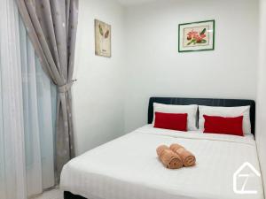 een slaapkamer met een wit bed met rode kussens bij 7th Avenue Stay (Sutera Avenue) in Kota Kinabalu