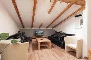 a living room with a black couch and a table at Haus Attos in Umhausen