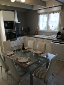 een keuken met een tafel met stoelen en een fles wijn bij La Glycine in Fouesnant