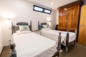 um quarto com 2 camas e um armário de madeira em Madeira Bird House - House in the Mountains With Garden em São Vicente