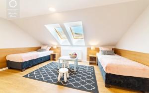 カルパチにあるWonder Home - Apartamenty z balkonami i ogródkami, blisko stoków narciarskich i szlaków turystycznychの屋根裏のベッドルーム(ベッド2台、テーブル付)
