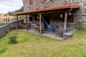 eine Terrasse mit Stühlen und einer Hängematte außerhalb eines Gebäudes in der Unterkunft Madeira Bird House - House in the Mountains With Garden in São Vicente