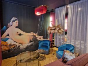 ein Wohnzimmer mit einem großen Gemälde eines Mannes auf einem Bett in der Unterkunft Le Boudoir D'Olympe Appartement érotico-romantique in Montauban
