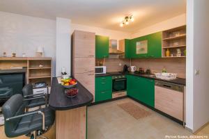 a kitchen with green cabinets and a desk with a chair at City break apartment in Čakovec