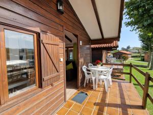 a wooden building with a patio with a table and chairs at Bungalows Playa de Oyambre in San Vicente de la Barquera