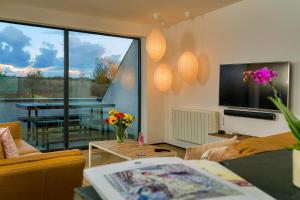a living room with a television and a table with flowers at Finest Retreats - Sand Barn in Stalham
