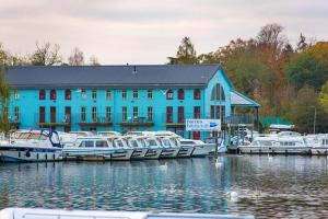 a blue building with boats docked in a marina at Finest Retreats - Sand Barn in Stalham