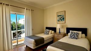 a bedroom with two beds and a window with a balcony at Ellegance by Check-in Portugal in Vilamoura