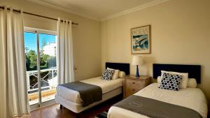 Un dormitorio con dos camas y una ventana con balcón. en Ellegance by Check-in Portugal, en Vilamoura