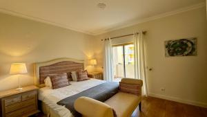 a bedroom with a bed with a chair and a window at Ellegance by Check-in Portugal in Vilamoura