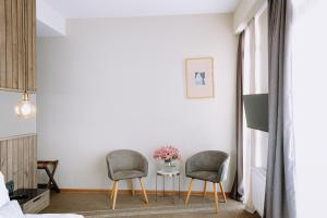 a bedroom with two chairs and a table with a vase of flowers at Hotel Sky Station in Tbilisi City