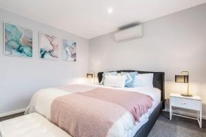 a white bedroom with a bed and a night stand at 'Caulfield Charm' Chic Inner-City Refuge in Melbourne