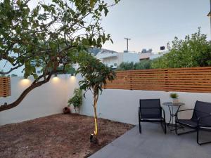 une terrasse avec 2 chaises, une table et un arbre dans l'établissement MG elounda apt, à Elounda