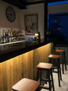 a bar with three stools at a counter in a bar at Lime Lite Manila Hostel in Manila