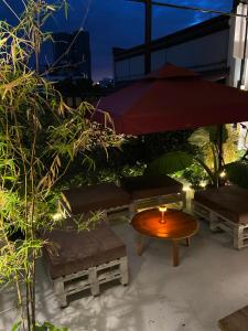 eine Terrasse mit einem Tisch, Bänken und einem Sonnenschirm in der Unterkunft Lime Lite Manila Hostel in Manila