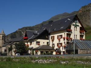 a large white building with black roofs and a church at Hotel Edelweiss in Arties
