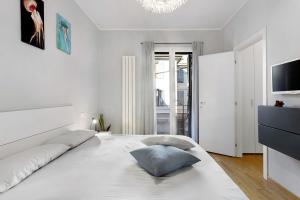 a white bedroom with a large bed and a television at La casetta di Ale in La Spezia