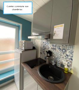 a kitchen with a sink and a microwave at Le Moment Douillet in Bourbourg