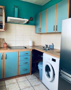 Studio tipa dzīvoklis في توكوموس: مطبخ مع دواليب زرقاء وغسالة ملابس