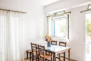 una mesa de comedor con sillas y un jarrón de flores en Margarita's Kionia Beach House, en Kionia