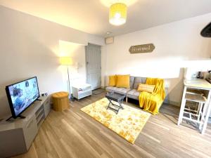 a living room with a couch and a tv at Stylish Cosy and Bright Apartment - Fantastic Location - Perfect for Business or solo travellers in Bishops Stortford