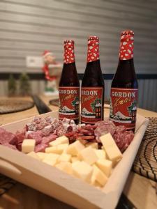 three bottles of beer and cheese on a cutting board at Gîte Chez Simone in Houffalize