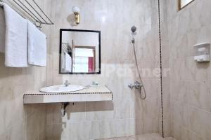 a bathroom with a sink and a shower with a mirror at Hotel Graha Muslim RedPartner in Bukittinggi