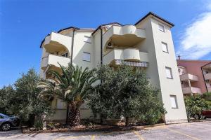 a white building with a palm tree in front of it at Apartment Damir - Novalja in Novalja