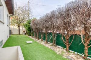 einen Garten mit Bäumen und einem grünen Zaun in der Unterkunft Magnifique studio 20 m2 - Paris - Disneyland in Noisy-le-Grand