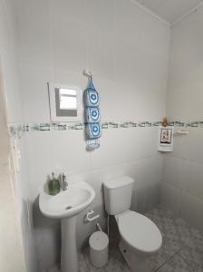 een witte badkamer met een toilet en een wastafel bij Casa com piscina in Peruíbe +18 foto's