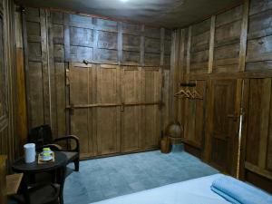 una camera da letto con pareti in legno, un letto e un tavolo di Puri Swantari Javanese Home Stay a Sleman