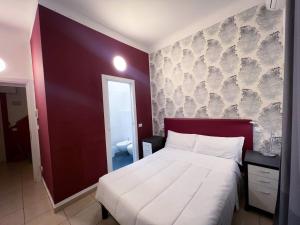 um quarto com uma cama grande e uma parede vermelha em Hotel RossoVino Milano em Milão