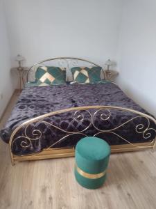 een slaapkamer met een bed met een blauwe deken en een groene kruk bij La Casa De Roland in Wieliczka