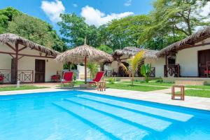 a pool with chairs and umbrellas in front of a house at Blue Sky Resort in Nosy Be